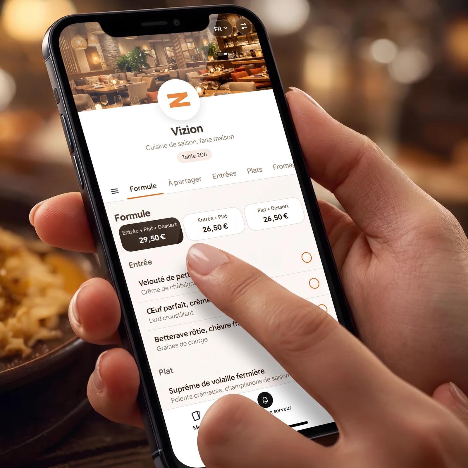 Une main tient un téléphone affichant la carte digitale Vizion, dans un restaurant